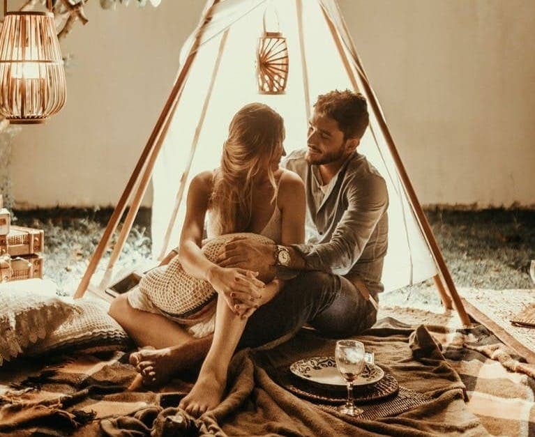 couple sitting inside tepee hut with lights