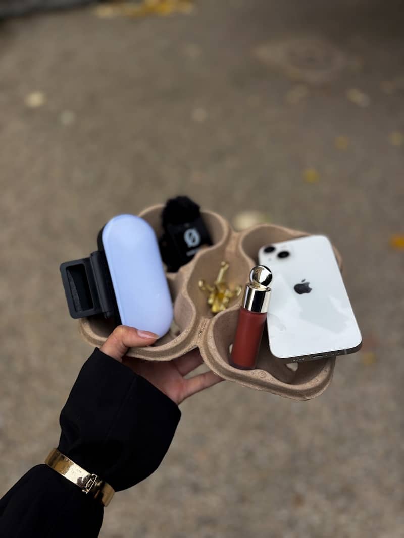 Hand holds tray with phone, light, and makeup.