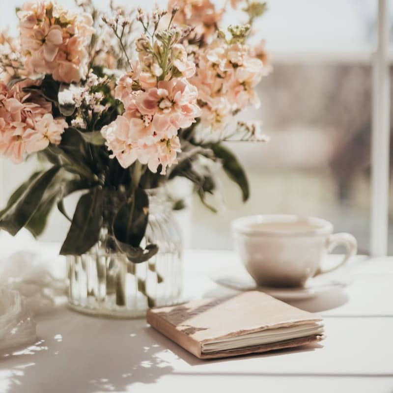 white and pink flowers on white ceramic teacup on white table