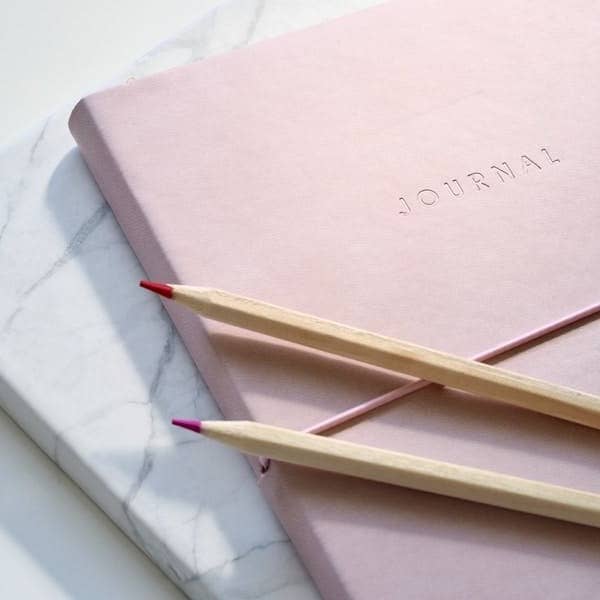 red and purple coloring pencils on pink journal