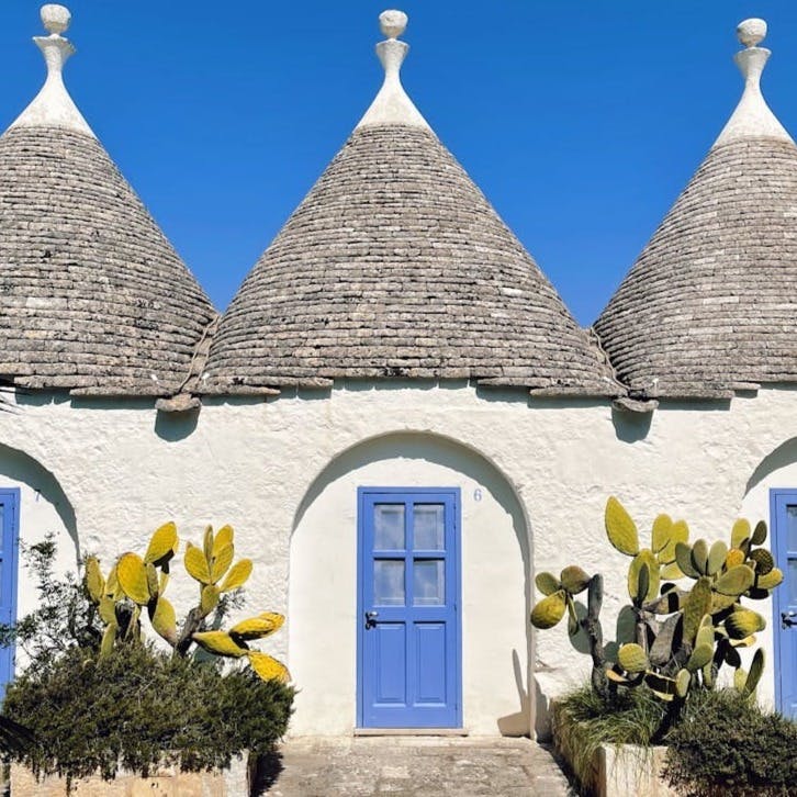 a house with blue doors and a roof with a blue door with Alberobello in the background