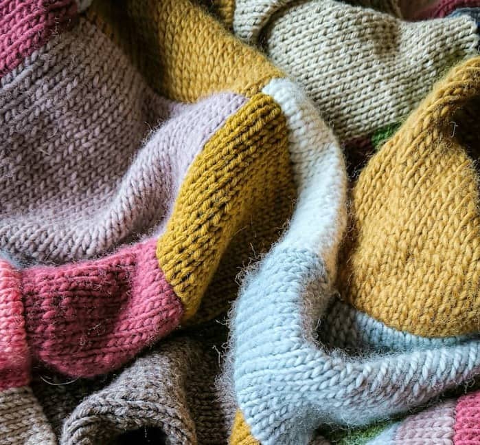 a knitted teddy bear laying on top of a blanket