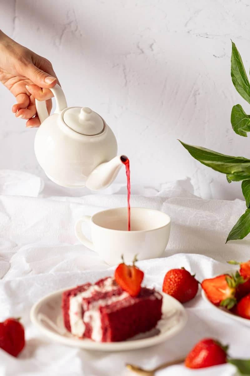 Pouring red tea with red velvet cake and fresh strawberries.