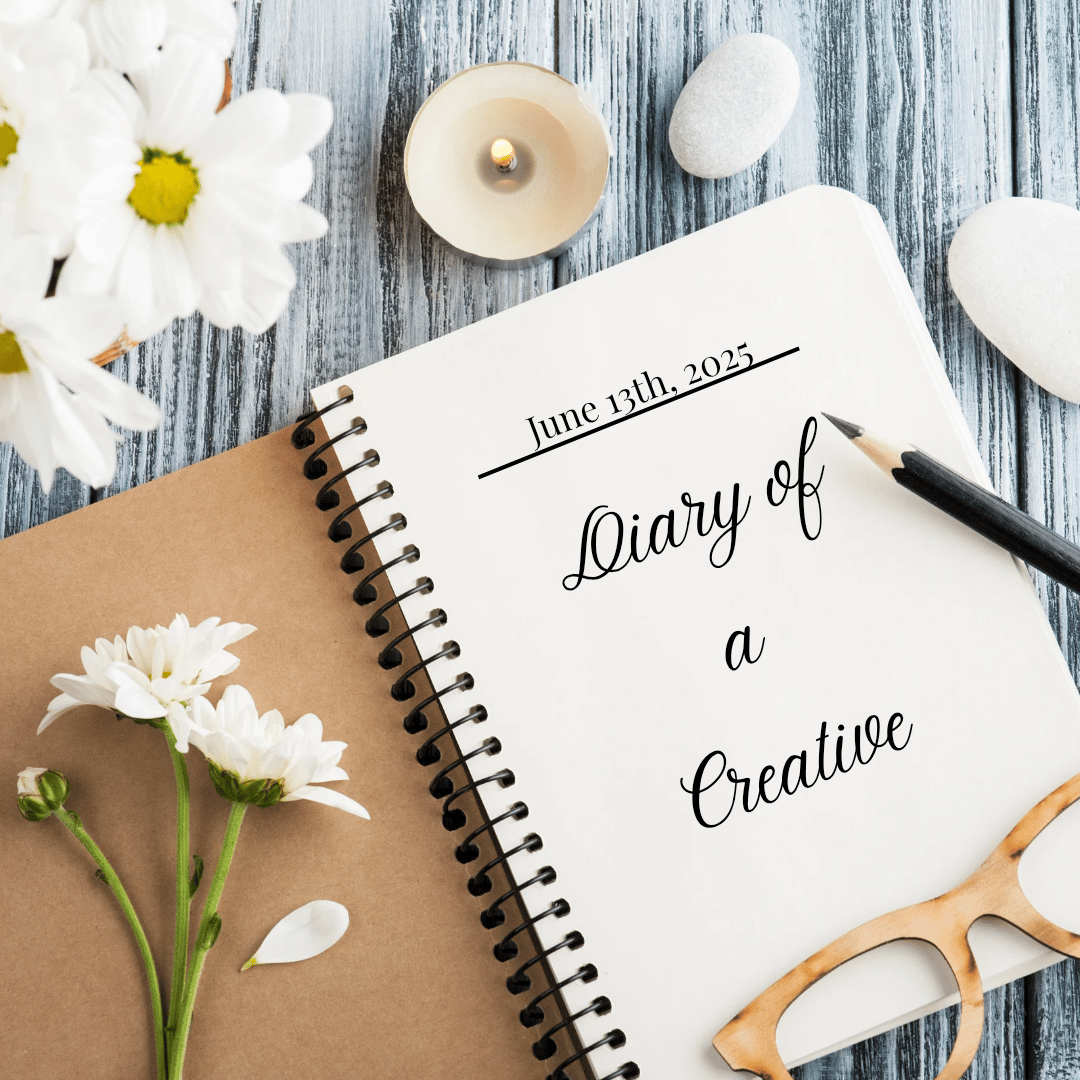 an open diary, flowers and a pen on a grey wooden table.