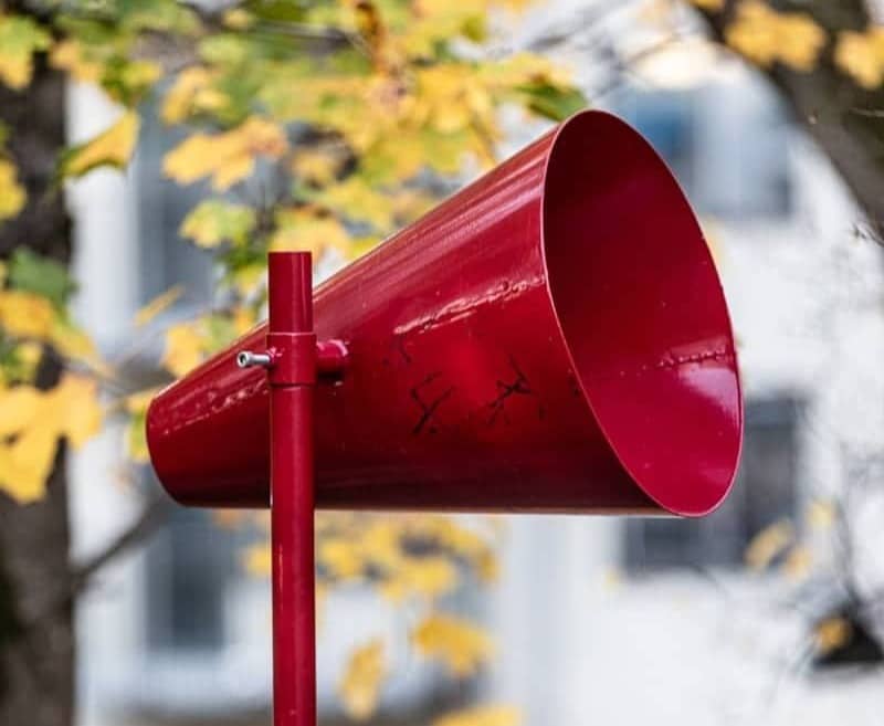 A red megaphone with a blurred city background.