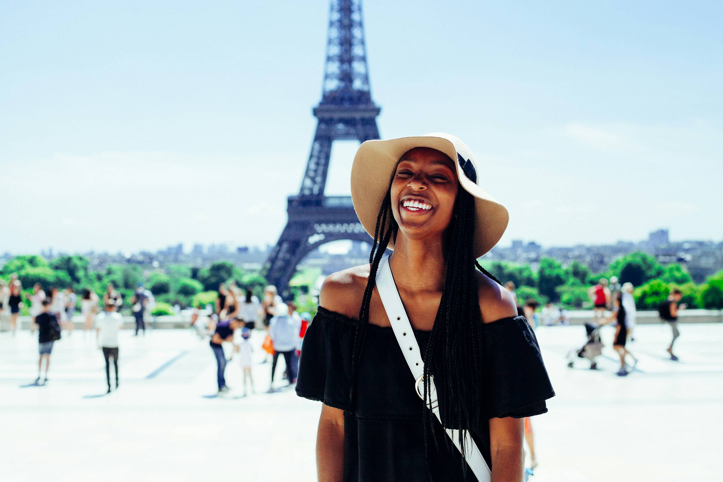 Woman in hat stood in front of Eiffel Tower smiling