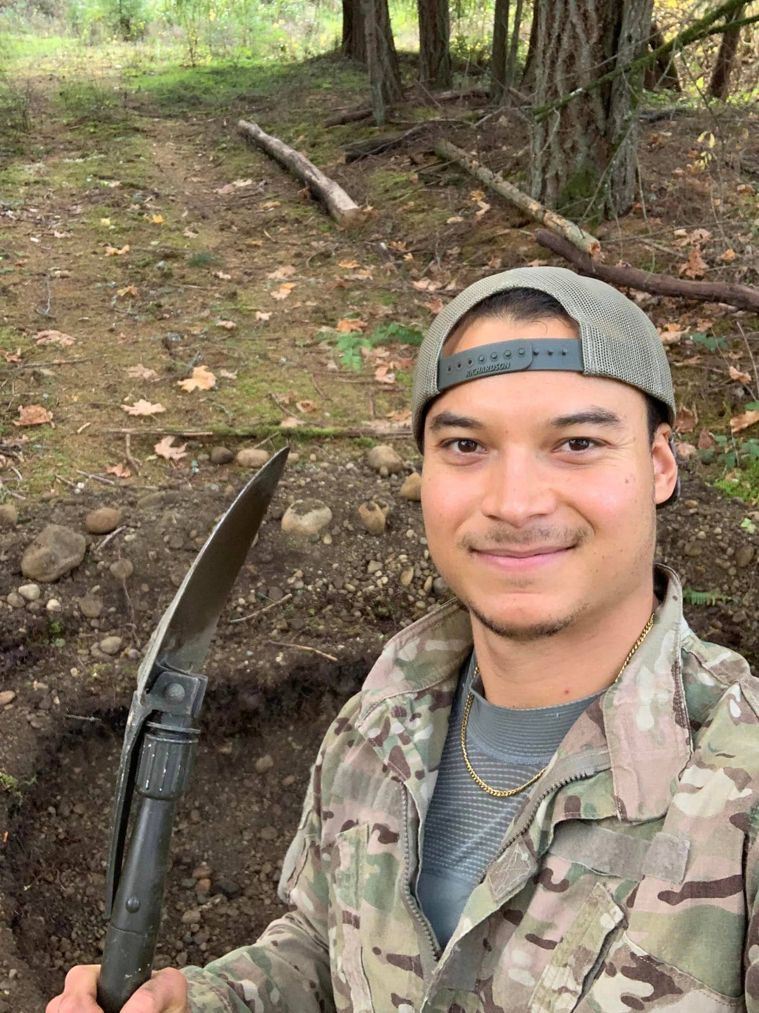 man smiling and holds a shovel after digging in the dirt