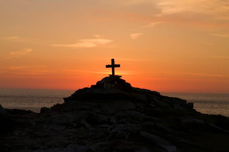 cross silhouette on mountain during golden hour