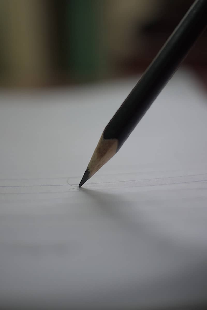 A pencil writing on a piece of paper