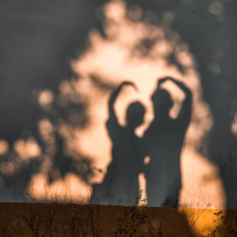 A shadow of two people standing in front of a tree