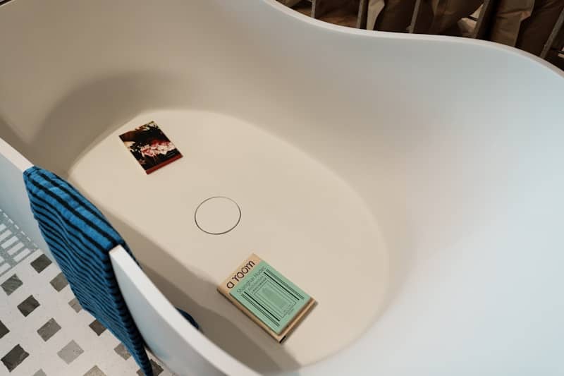 An empty bathtub with a towel and books.