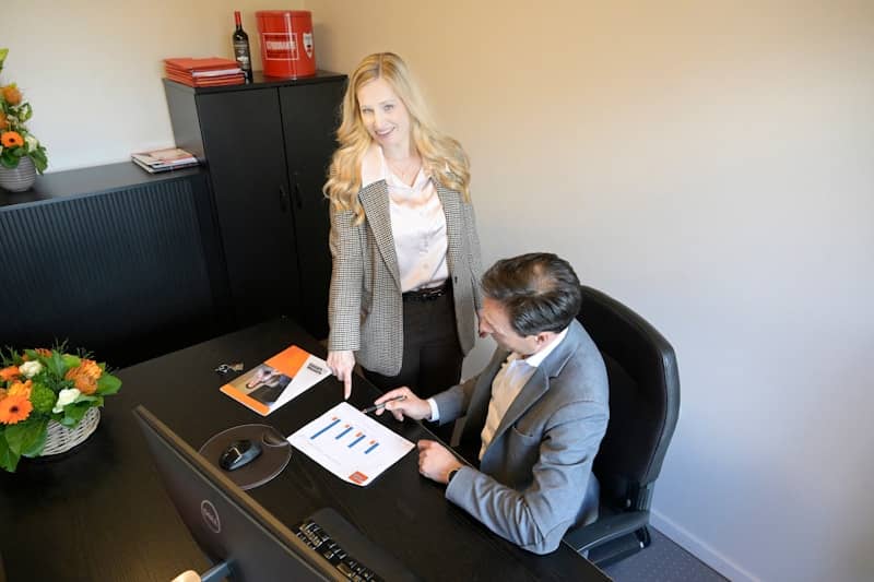 Businesswoman pointing at documents for businessman in office.