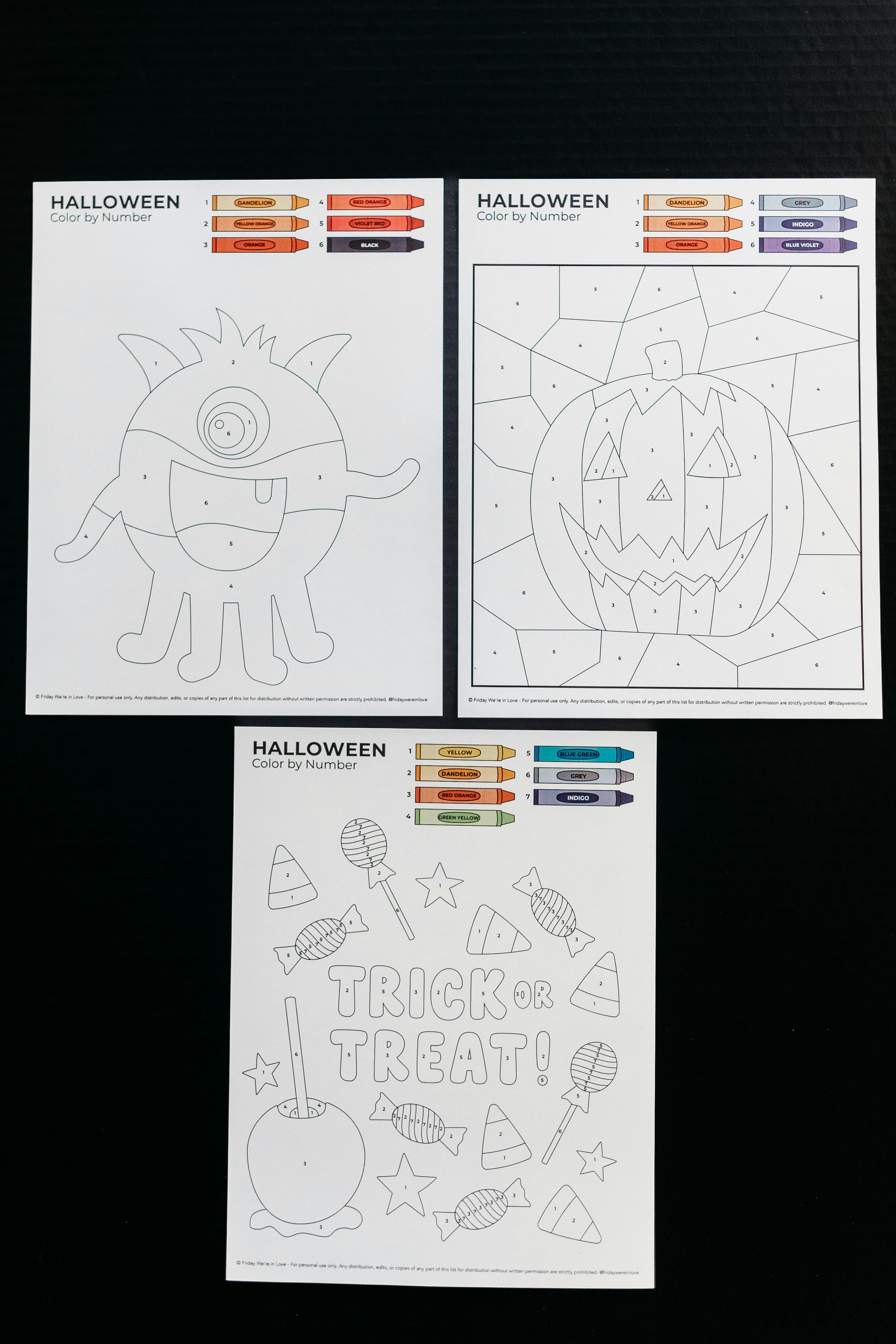 Three versions of Halloween color by number printed and laid side by side on a black background. 