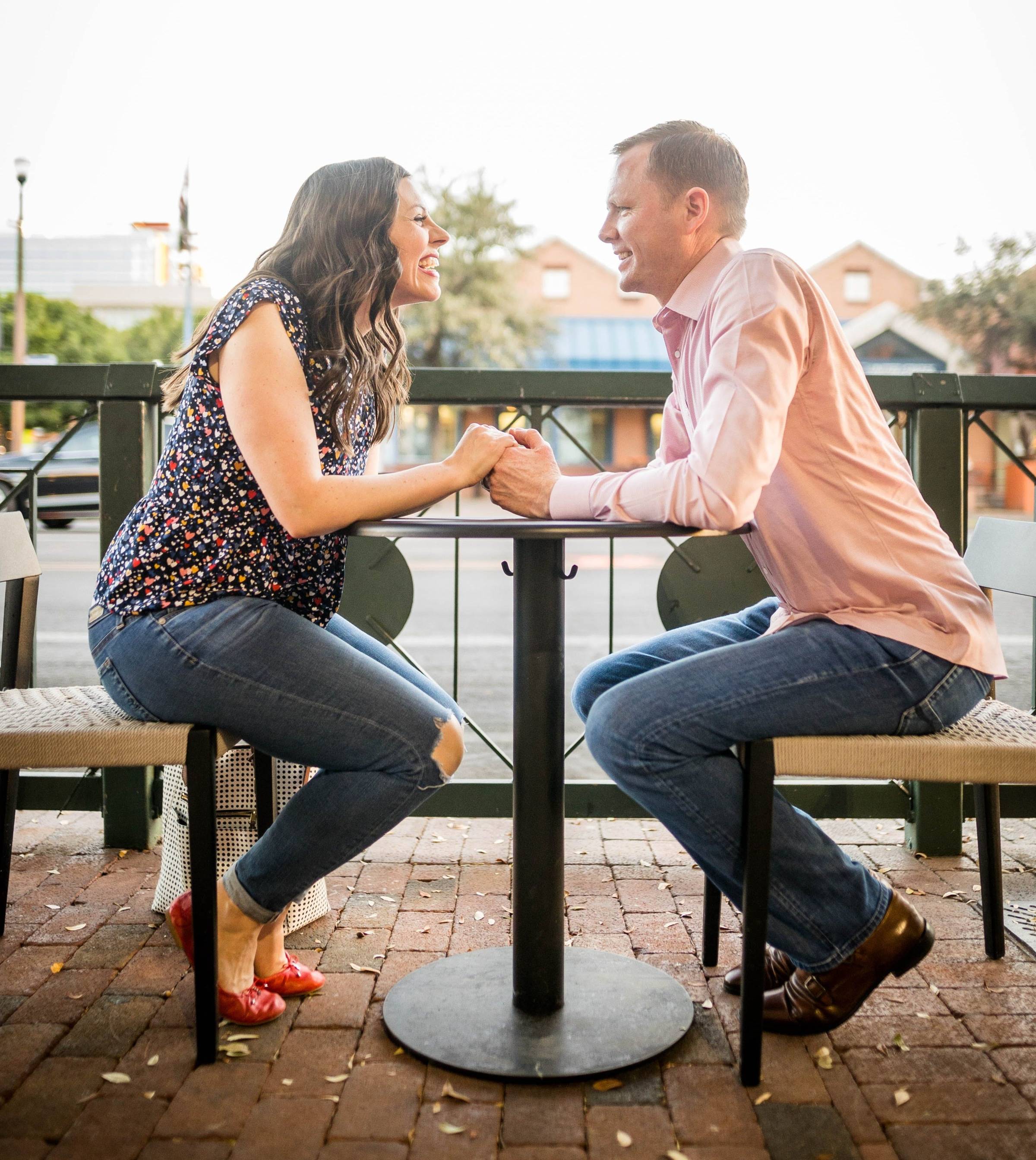 Husband and wife out on a date night enjoying dinner on a patio. 