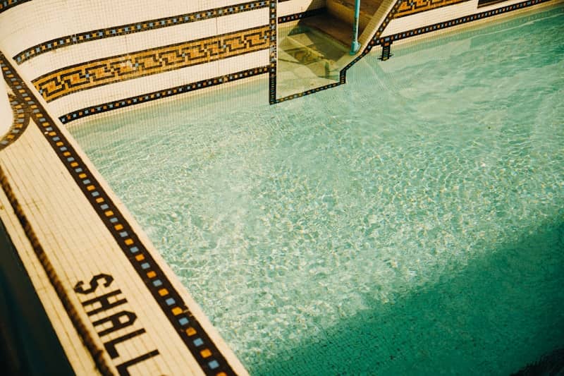 A vintage swimming pool with decorative tiles and clear water.