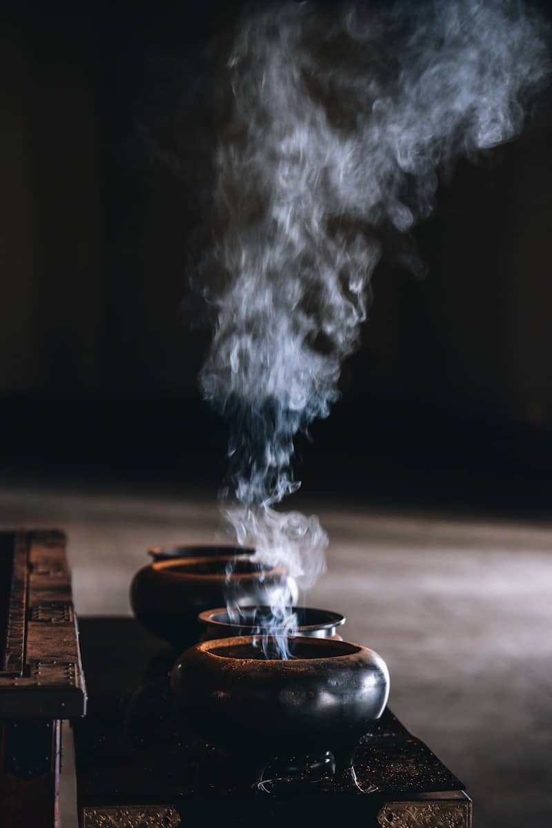 Smoke rising from three incense burners in a row.
