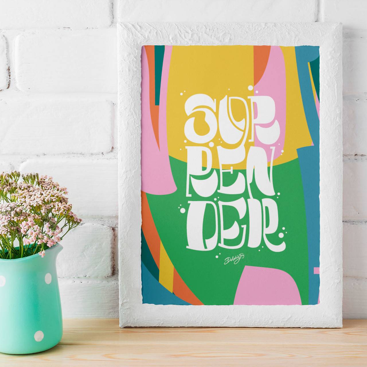 A framed handlettered artwork of a colourful print with SURRENDER written on it.