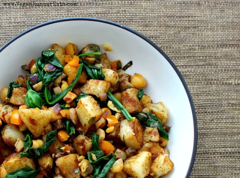 A bowl with vegan warm potato salad made with spinach and chickpeas