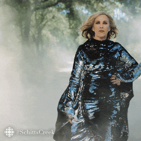 moira from schitt's creek walking confidently in a dress that looks like a garbage bag