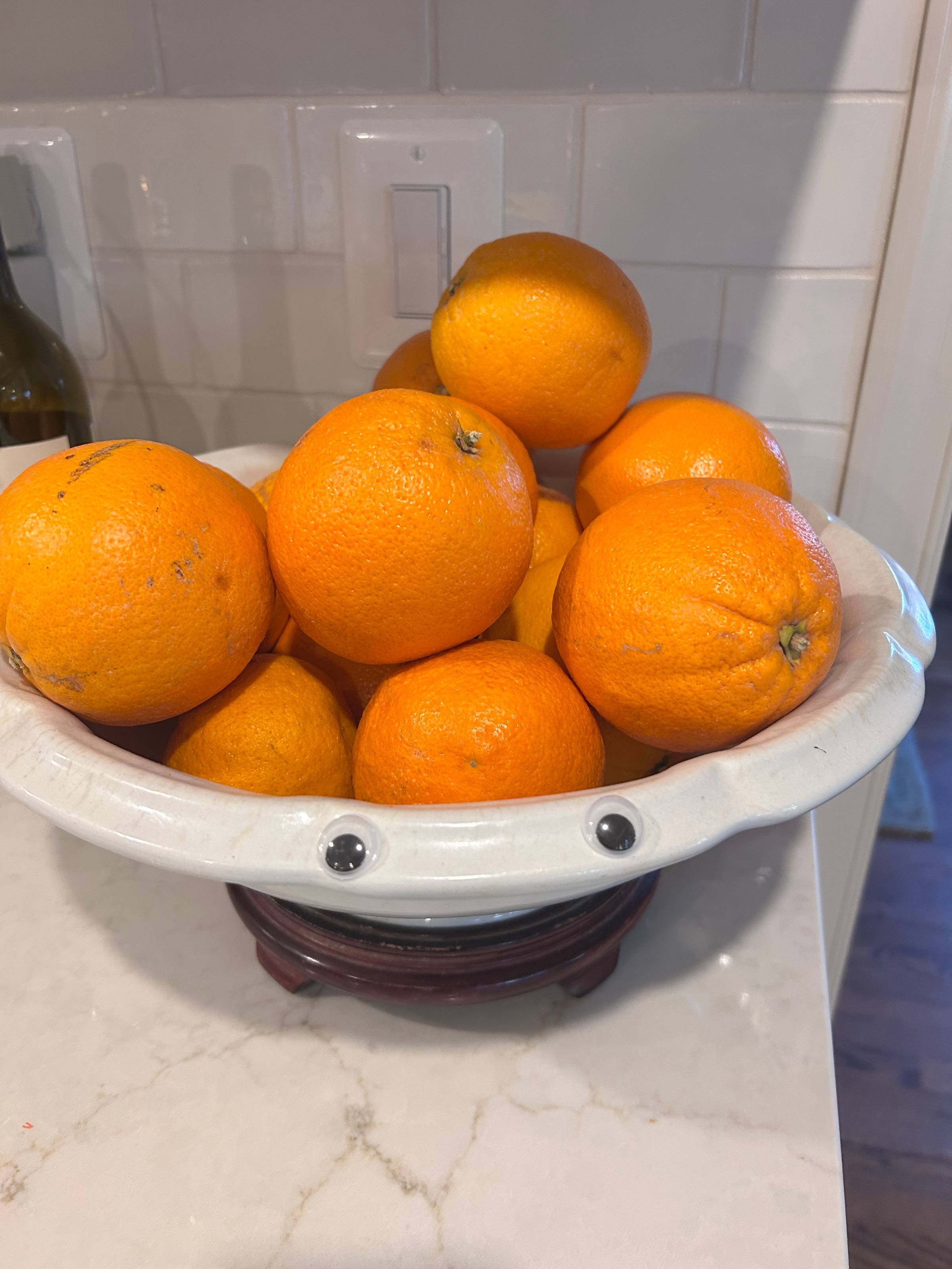 googly eyes  on a bowl of oranges