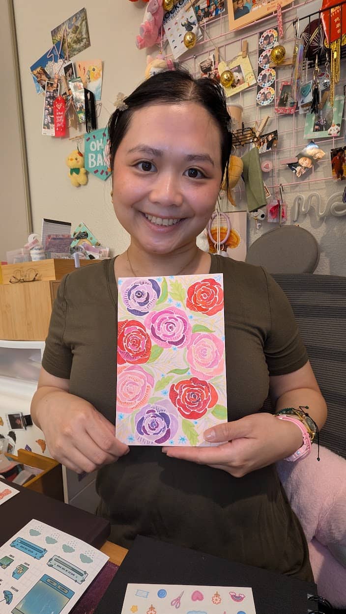 Headshot image of the artist holding a drawing of roses