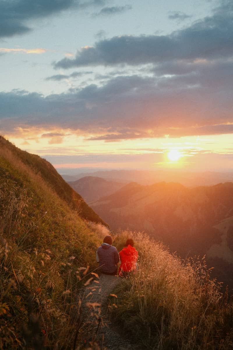 Two people on a mountain trail in Schwende-Rüte, Switzerland, during the golden hour