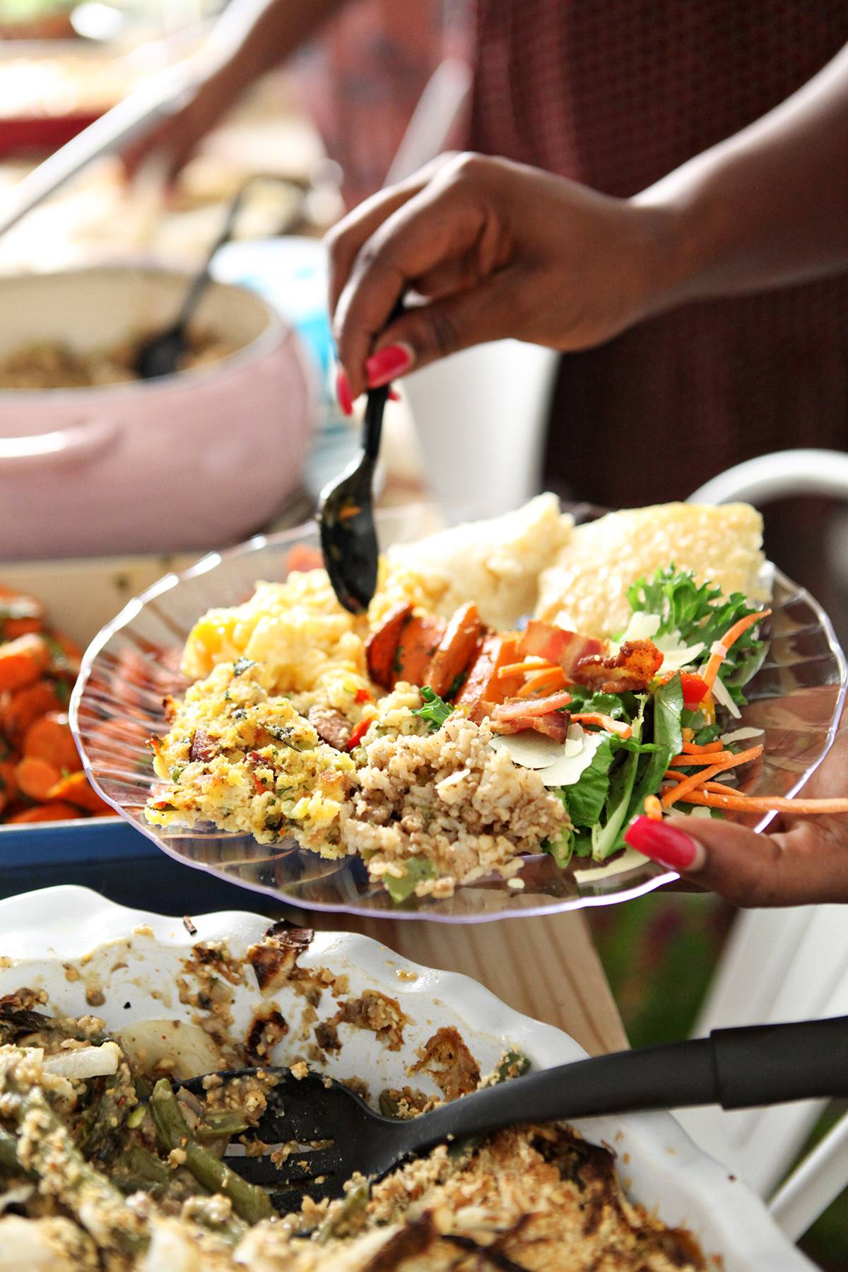 A woman loads Friendsgiving food onto her plate