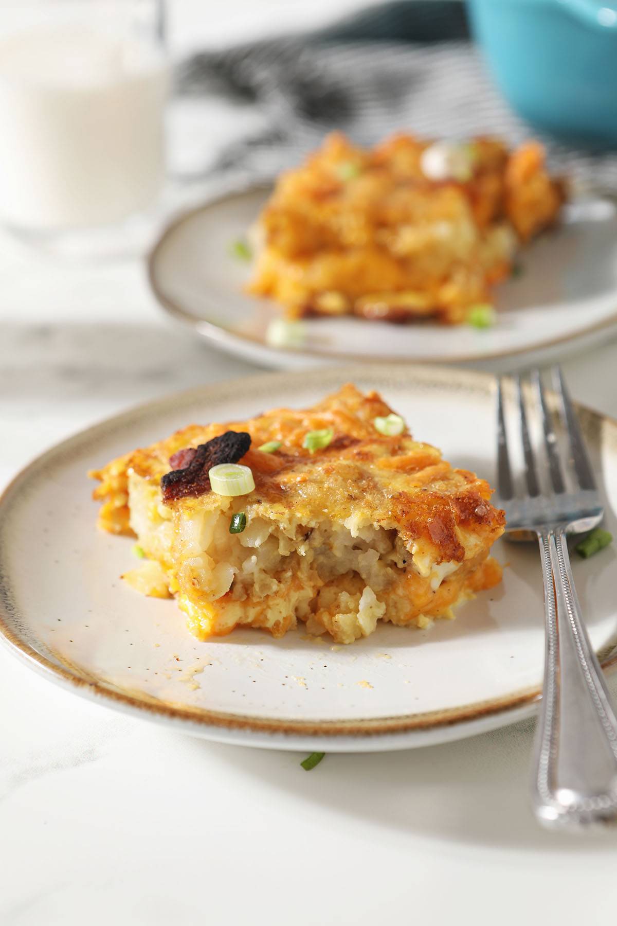 A slice of tater tot breakfast casserole on a plate with a fork