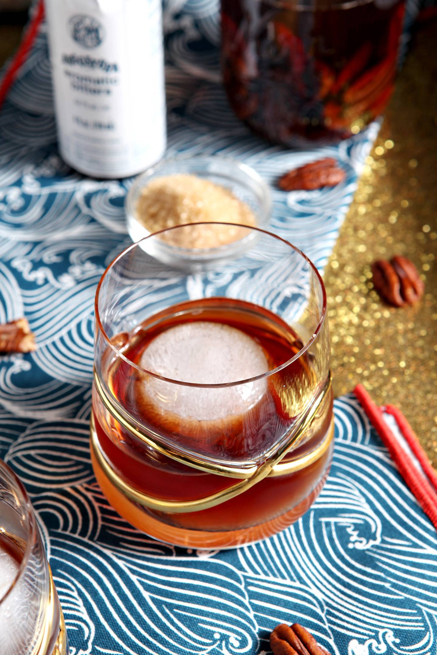 an old fashioned surrounded by pecans on a gold tray