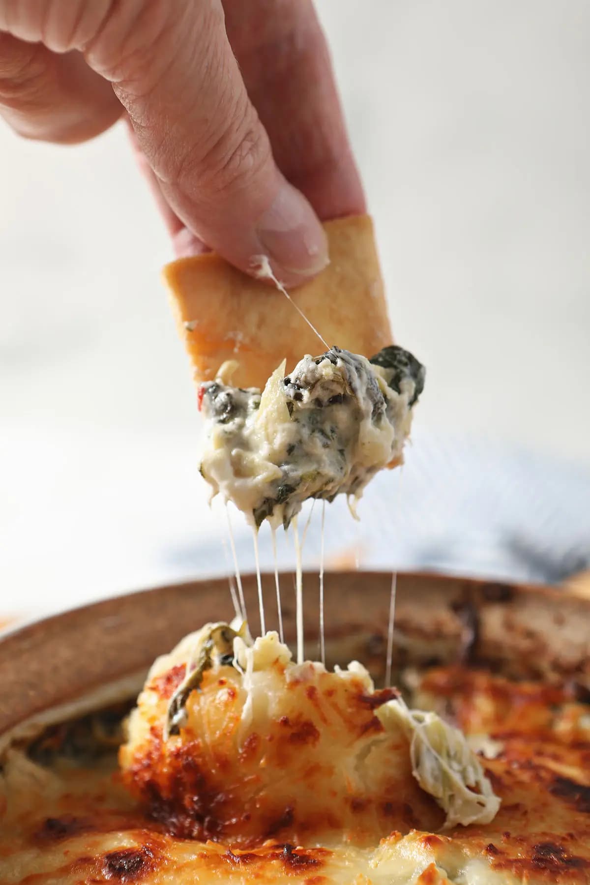 A crispy pita cracker dips into gooey spinach artichoke dip. 