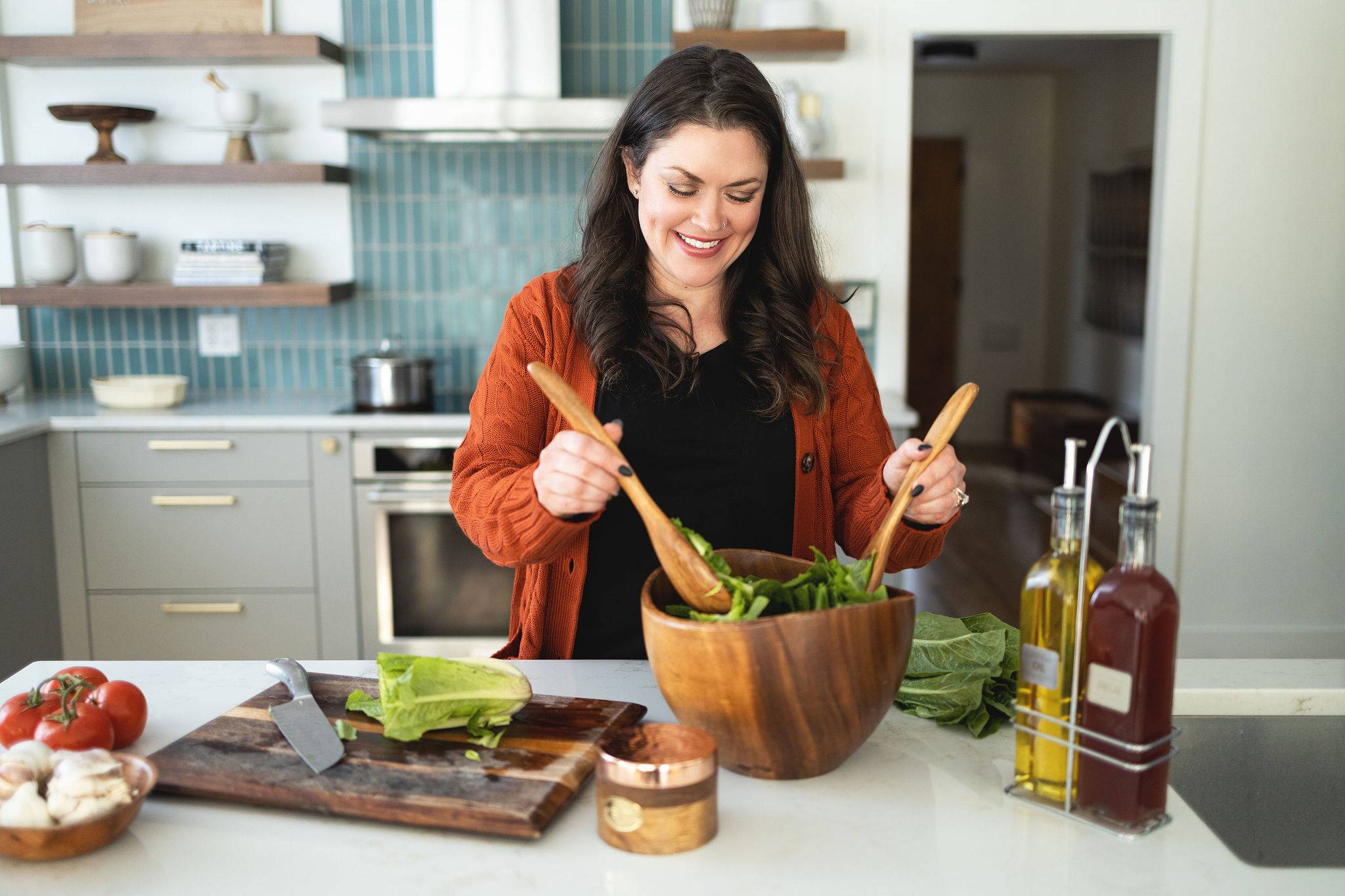 amanda scarlati tossing a salad in a bowl in a kitchen.