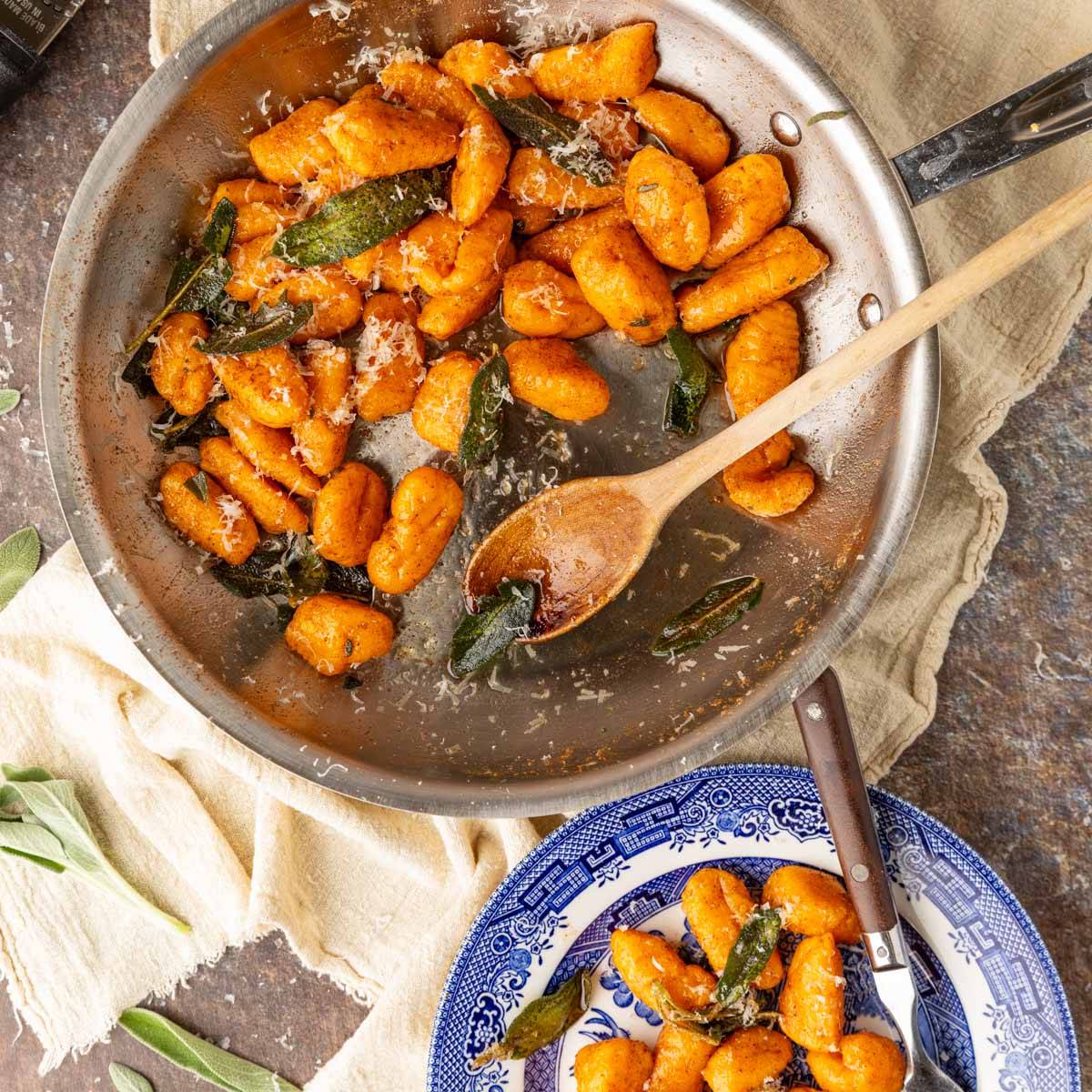 sweet potato gnocchi in a skillet and bowl with fried sage and grated cheese.