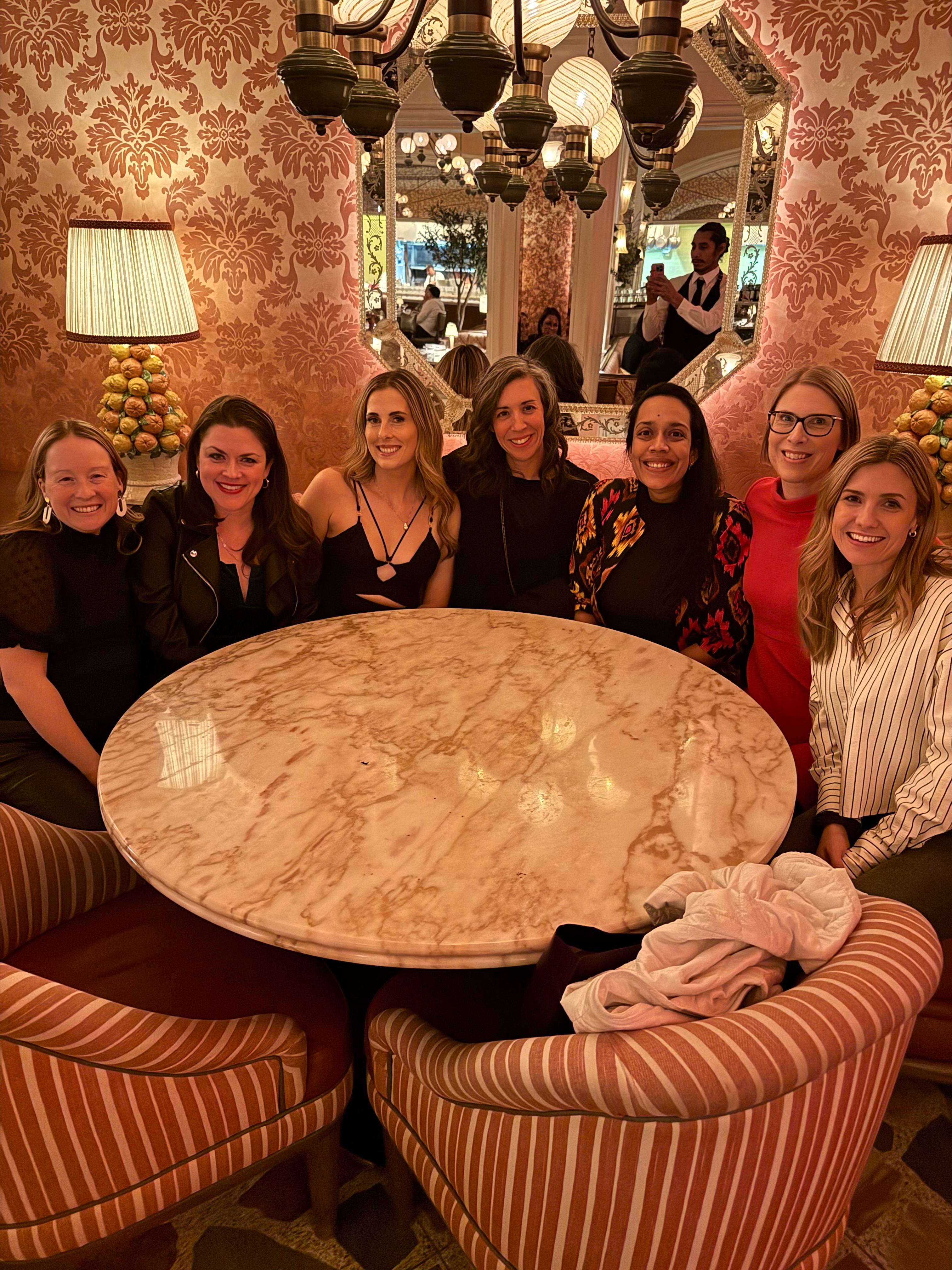 Amanda Scarlati with six other women sitting around a table in a restaurant.