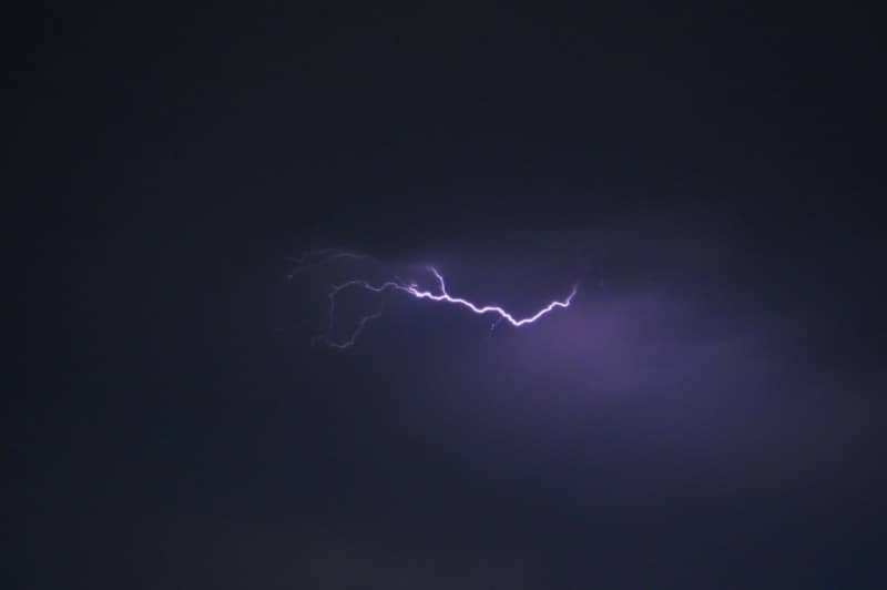 A bright purple lightning bolt across a dark night sky