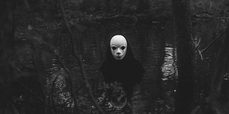 A person with a creepy mask standing in the woods