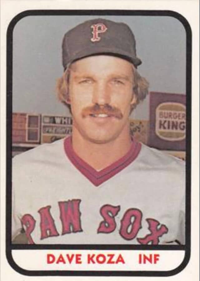 Vintate baseball card for Dave Koza, infielder, of the Pawtucket Red Sox circa 1981. Dave has a thick blond mustache. Behind him is the scoreboard and a sign advertising Burger King. 