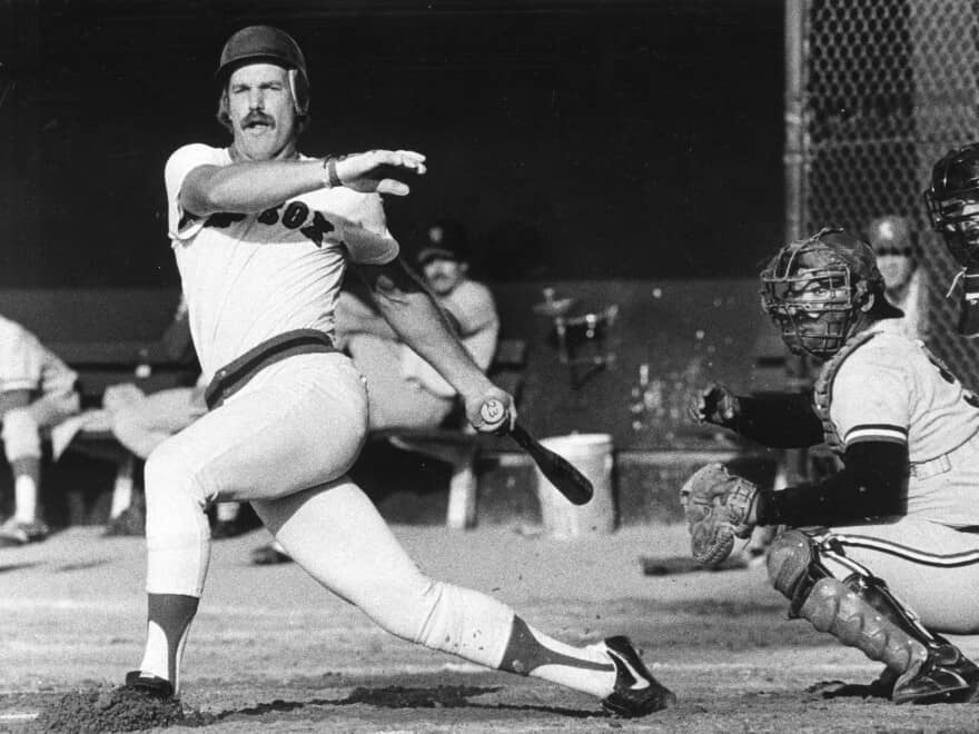 Black and white photo of a baseball game in 1981 that was published in the Boston Globe. Infielder Dave Koza finishes his swing and gets ready to run to first base. 