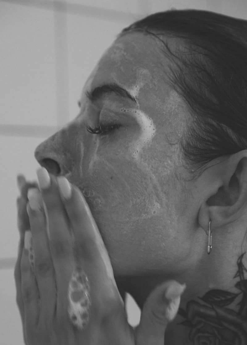 Woman washing her face with a foamy cleanser.