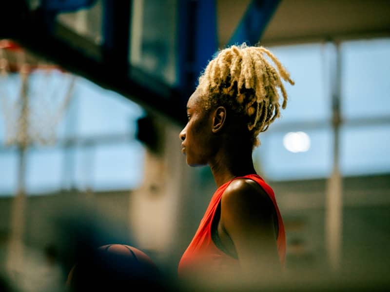 A woman with dreadlocks standing in front of a basketball hoop