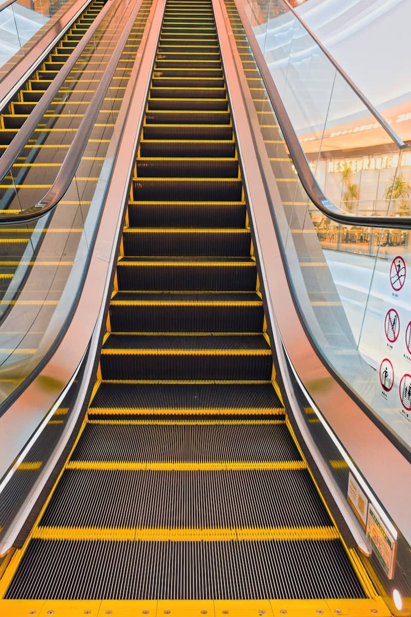 An empty escalator going upwards with yellow stripes.