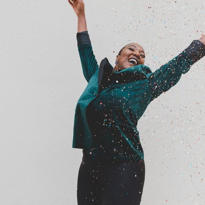 woman in green jacket raising her hands