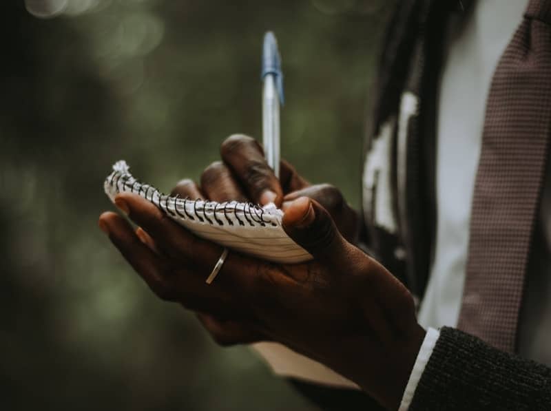 Person writing notes in a notebook outdoors