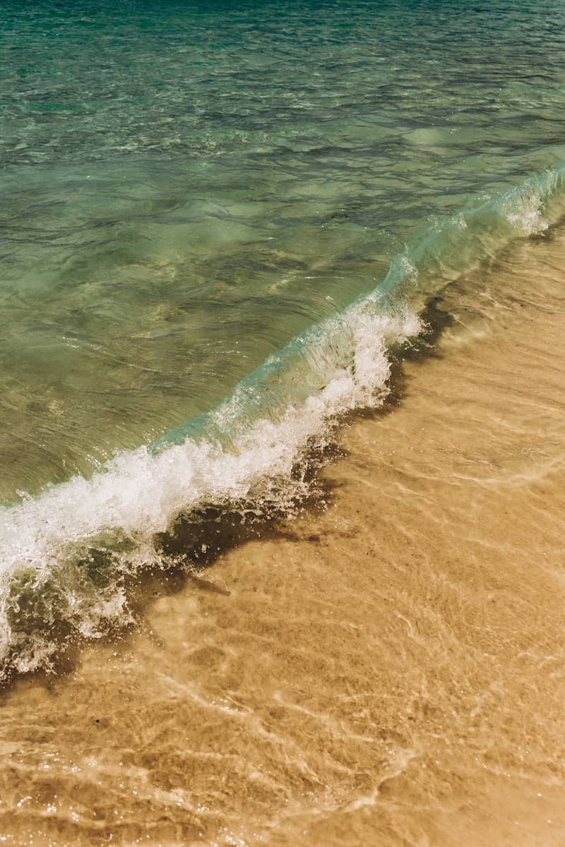 A gentle wave washes onto a sandy beach.