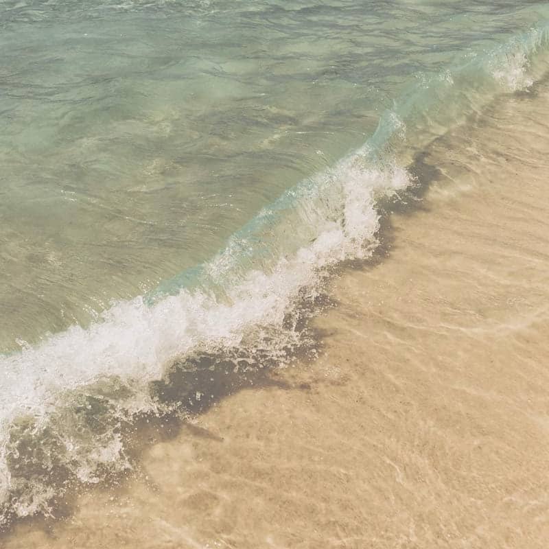 A gentle wave washes onto a sandy beach.