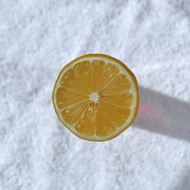 A single lemon slice on a white surface