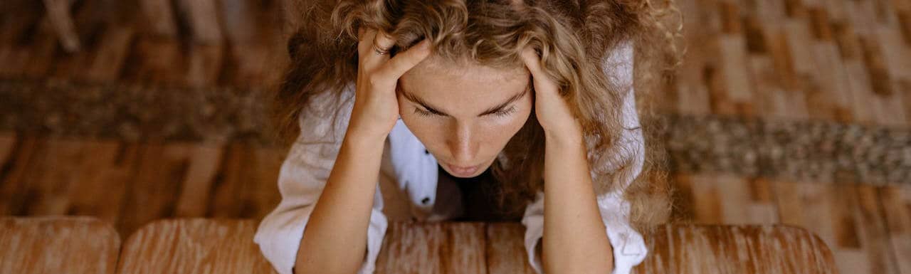 Lady holding her head in her hands.