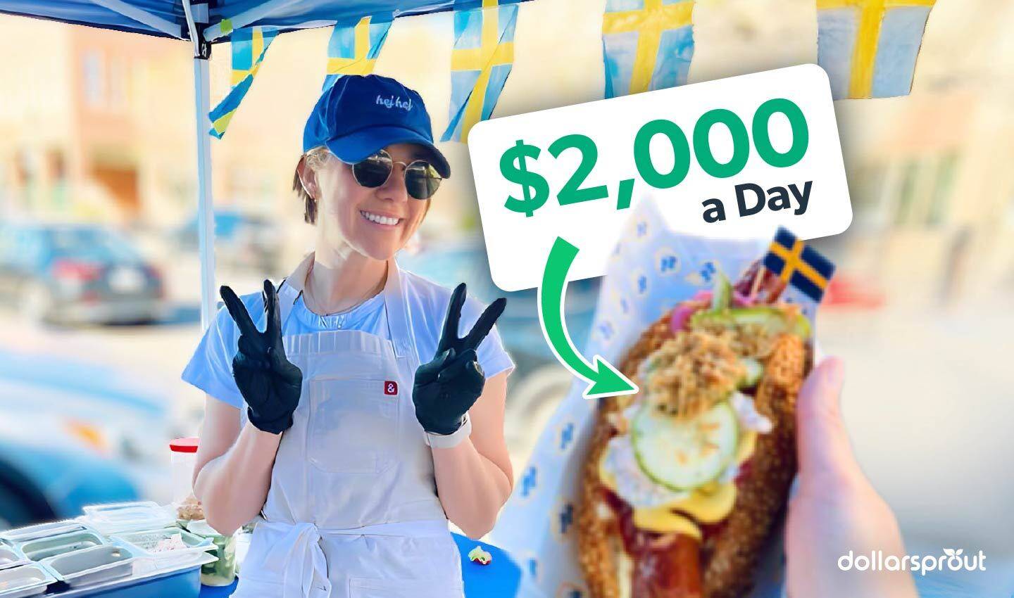 Amelia Eudailey, founder of Chef Hej Hej, smiling and flashing peace signs at her Swedish hot dog pop-up stand, with a fully loaded hot dog in the foreground.