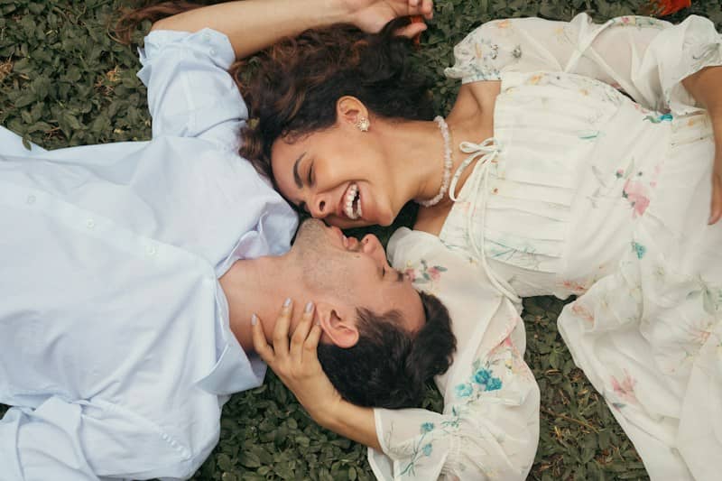 A woman and a man lying on green grass, laughing together