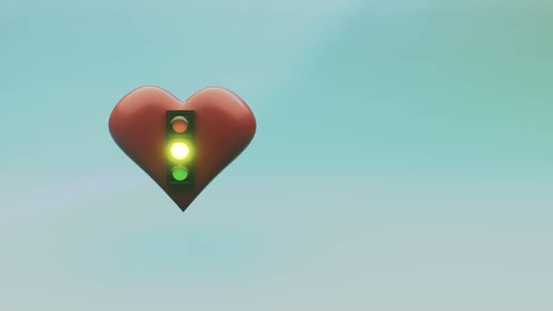 Red heart with green traffic light symbol against blue background.