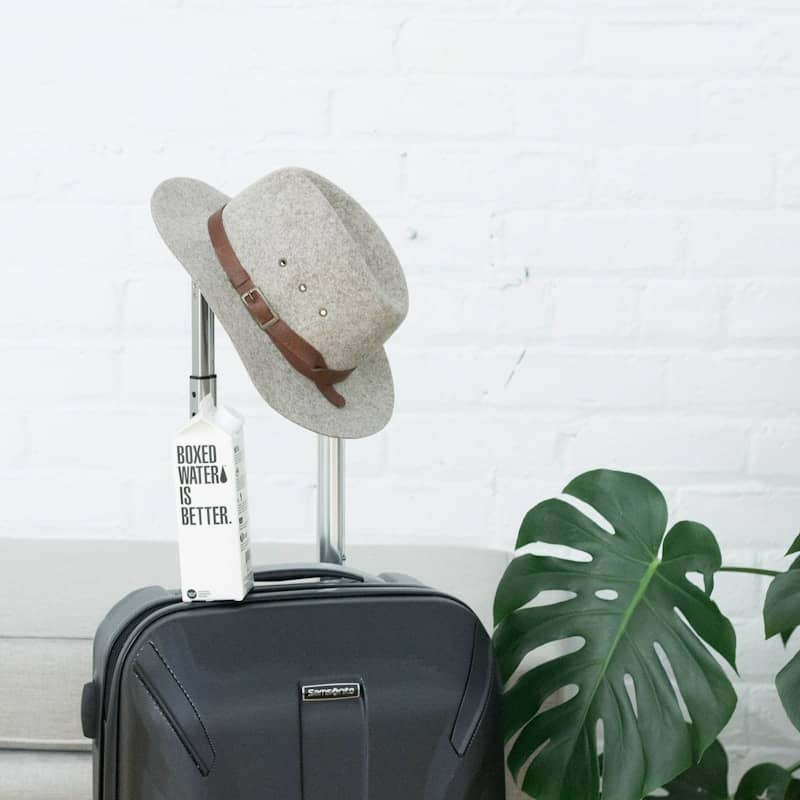 A hat and boxed water carton sit on a suitcase